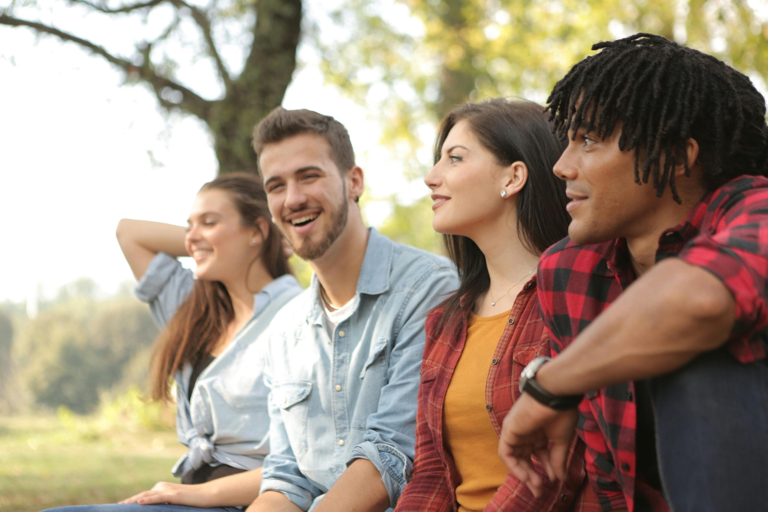 A diverse group of friends laughing and enjoying a sunny day in a park.